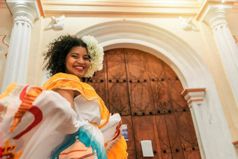 年轻的混血儿女人卷曲的黑色的头发教堂利昂尼加拉瓜穿传统的黄色的衣服相机微笑概念跳舞文化传统