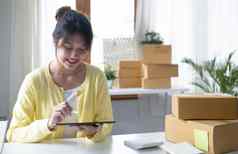 肖像业务亚洲女人微笑平板电脑检查信息包裹航运盒子发送客户企业家小业务工作首页锻造业务在线市场营销
