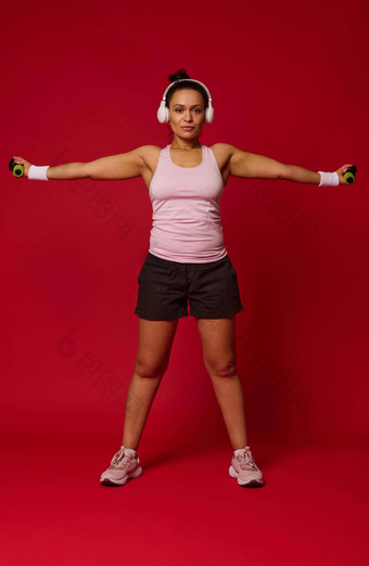 完整的长度身体大小视图活跃的女运动员锻炼哑铃红色的背景复制空间广告文本