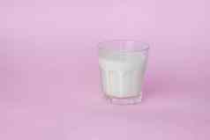玻璃白色牛奶突出显示粉红色的背景特写镜头