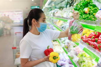 亚洲女人长头发穿保护脸面具超市部门商店女杂货店买水果正常的科维德家庭概念