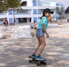 亚洲女孩玩冲浪滑冰董事会公园滑冰斜坡在户外早....快乐女孩玩冲浪溜冰董事会公园体育运动活动生活方式概念