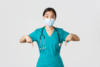 科维德冠状病毒疾病医疗保健工人概念兴奋惊讶亚洲女医生护士实习医生风云医疗面具指出手指显示广告