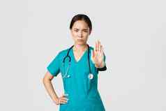 科维德医疗保健工人流感大流行概念愤怒的严肃的表情亚洲医生女医生护士实习医生风云皱着眉头不高兴扩展手显示停止不同意禁止禁止