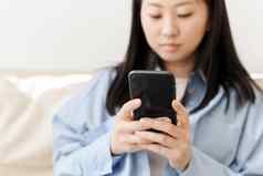 亚洲年轻的女人浏览社会媒体购物在线检查应用程序游戏智能手机支出时间首页放松免费的时间