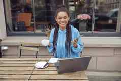 肖像年轻的快乐女杯咖啡移动电话移动PC自助餐厅