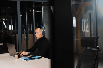 亚洲男人。耳机工作在线听音乐办公室亚洲英俊的的家伙移动PC共同<strong>办公空间</strong>