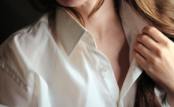 美丽的浅黑肤色的女人倾斜头解开<strong>扣子</strong>领白色衬衫