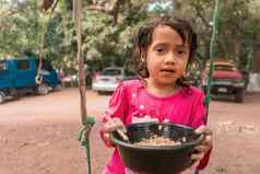 拉丁女孩坐着摇摆不定的吃塑料碗概念童年营养食物农村区域