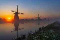 传统的荷兰风车色彩鲜艳的天空日出小孩堤防荷兰