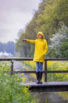 年轻的女人黄色的雨衣橡胶靴子春天自然