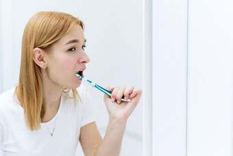 年轻的快乐的女人刷牙牙齿牙刷早....卫生程序浴室