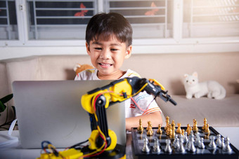 亚洲男孩编程代码机器人机手臂移动PC玩国际象棋