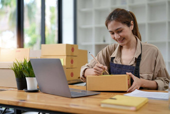 年轻的微笑美丽的老板亚洲女人自由锻造业务在线购物工作移动PC电脑包裹盒子桌子上首页锻造业务在线交付概念