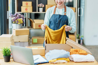 肖像小启动亚洲女企业家锻造老板挑选黄色的衬衫包装盒子客户在线业务的想法自由