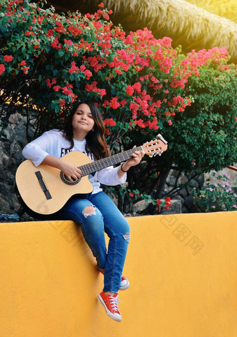 女孩坐着玩吉他在户外肖像微笑女孩玩吉他生活方式女孩玩吉他在户外