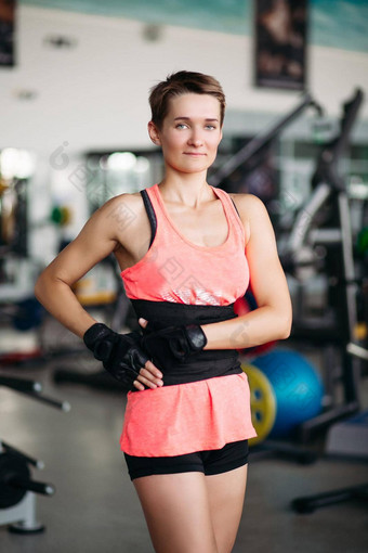 运动女人强大的身体穿粉红色的t恤摆姿势相机年轻的运动适合女孩健身房模拟器概念体育运动健身
