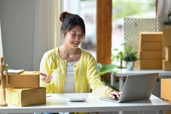 微笑年轻的女企业家检查在线订单数字平板电脑准备包裹盒子交付客户