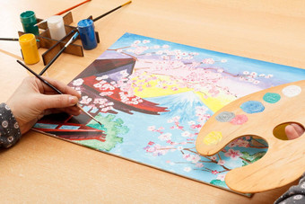 女人的手绘画风景如画的日本景观在室内