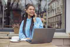 快乐的年轻的混血时尚的女人聊天电话咖啡工作移动PC