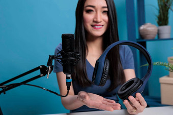 亚洲视频博客创造者持有耳机会说话的工作室麦克风