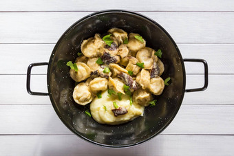 俄罗斯食物水饺肉饺子蘑菇酱汁被捣成糊状的土豆黑色的碗特写镜头前视图