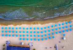 空中前视图美丽的小海滩蓝色的雨伞海波