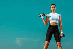 运动适合年轻的女人运动员培训哑铃天空背景概念健康的生活方式体育运动个人体育娱乐