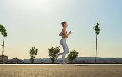 慢跑运行强大的运动女人运行天空背景穿运动服装健身体育运动动机跑步者概念