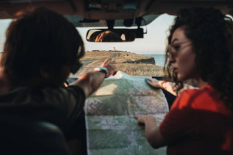 回来视图男人。女人坐着车检查地图年轻的夫妇享受路旅行