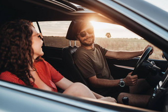 快乐的男人。卷曲的浅黑肤色的女人女人坐着车年轻的夫妇享受路旅行日落