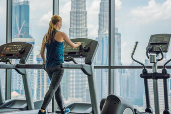 体育运动健身生活方式技术人概念女人锻炼跑步机健身房背景大城市