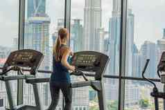 体育运动健身生活方式技术人概念女人锻炼跑步机健身房背景大城市