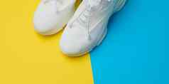 白色纺织运动鞋蓝色的黄色的背景前视图