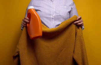 女人白色条纹衬衫持有橙色塑料瓶<strong>液</strong>体洗过来这里针织毛衣<strong>洗衣</strong>家庭家务清洁洗项目
