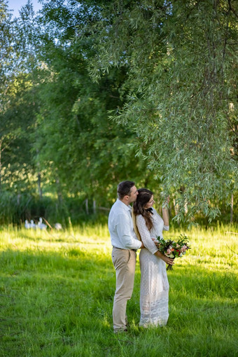 新娘新郎婚礼一天走在户外新娘夫妇快乐新婚女人男人。拥抱绿色公园爱的婚礼夫妇户外