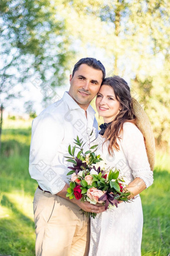 肖像美丽的新婚夫妇站绿色草地抱住乡村婚礼