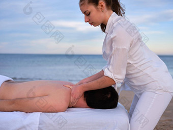 年轻的chiromassage治疗师给肩膀按摩年轻的男人。海滩瓦伦西亚