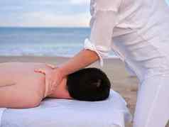 年轻的男人。接收肩膀按摩女chiromassage治疗师海滩瓦伦西亚