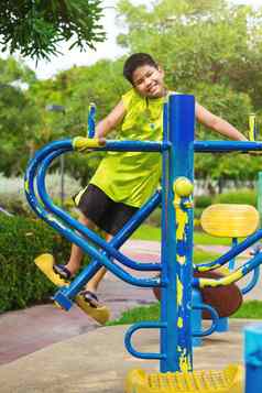 快乐亚洲体育运动男孩玩摇摆不定的操场上花园
