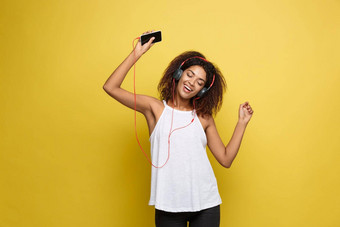 生活方式概念肖像美丽的非洲美国女人快乐的听<strong>音乐</strong>移动电话黄色的<strong>柔和</strong>的工作室背景复制空间