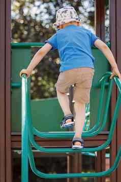 男孩蓝色的t恤大胆地爬操场上管状绿色梯孩子害怕风险