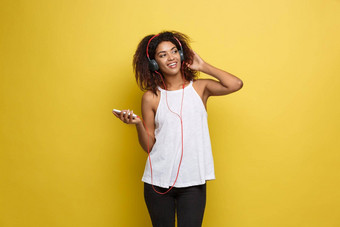 生活方式概念肖像美丽的非洲美国女人快乐的听音乐移动电话黄色的柔和的工作室背景复制空间