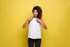 美丽的有吸引力的非洲美国女人发布穿着白色t恤黄色的工作室背景复制空间