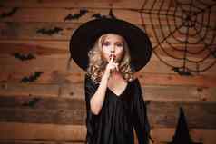 万圣节女巫概念特写镜头拍摄高加索人女巫孩子持有指数手指嘴唇沉默