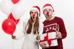 圣诞节概念年轻的高加索人夫妇持有礼物香槟气球使有趣的脸圣诞节