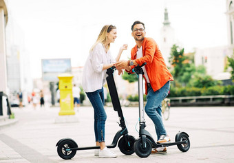 夫妇年轻的电踏板车城市运输骑技术生活方式街朋友开车现代
