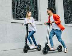 夫妇年轻的电踏板车城市运输骑技术生活方式街朋友开车现代