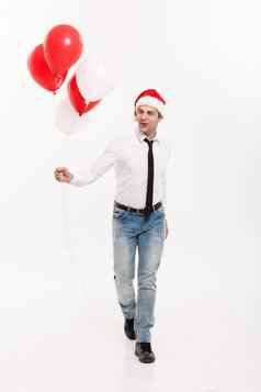 圣诞节概念英俊的快乐业务男人。走红色的气球庆祝快乐圣诞节快乐一年穿圣诞老人他