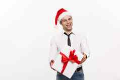 圣诞节概念英俊的快乐业务男人。给礼物穿圣诞老人他摆姿势白色孤立的背景